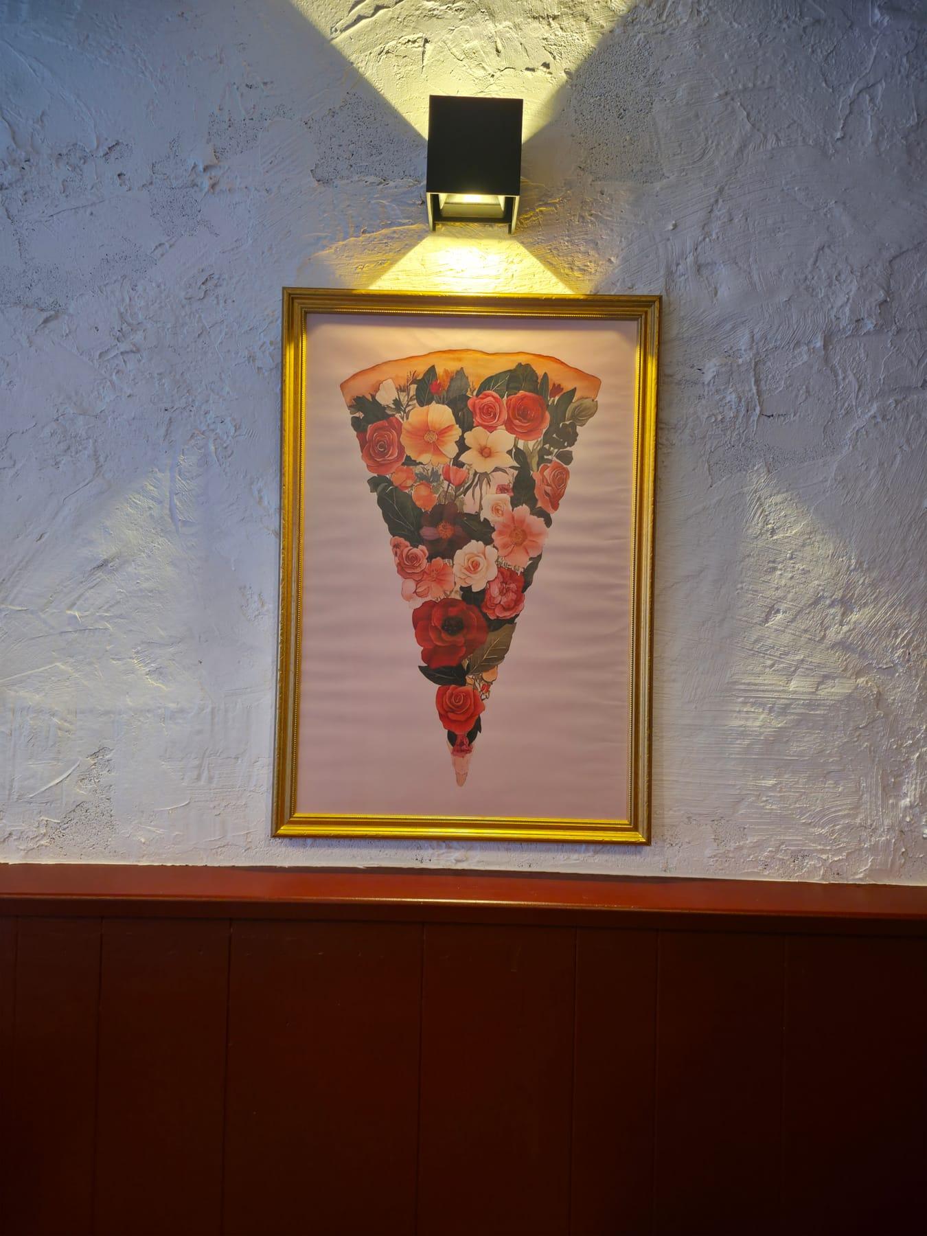 Décoration intérieure de Mémé Rina : part de pizza composée de fleurs, encadrée et éclairée