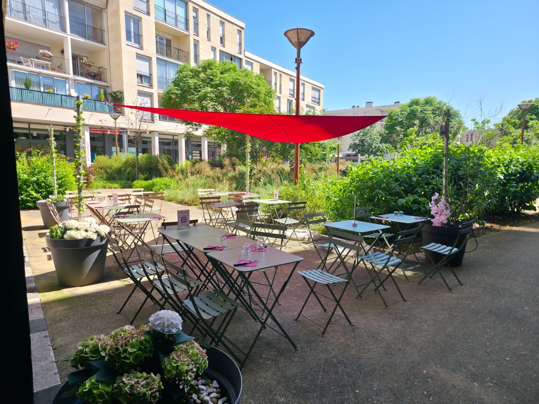 La terrasse d'été de la Pizzeria Mémé Rina à Chatou, tables vertes installées face aux jardins